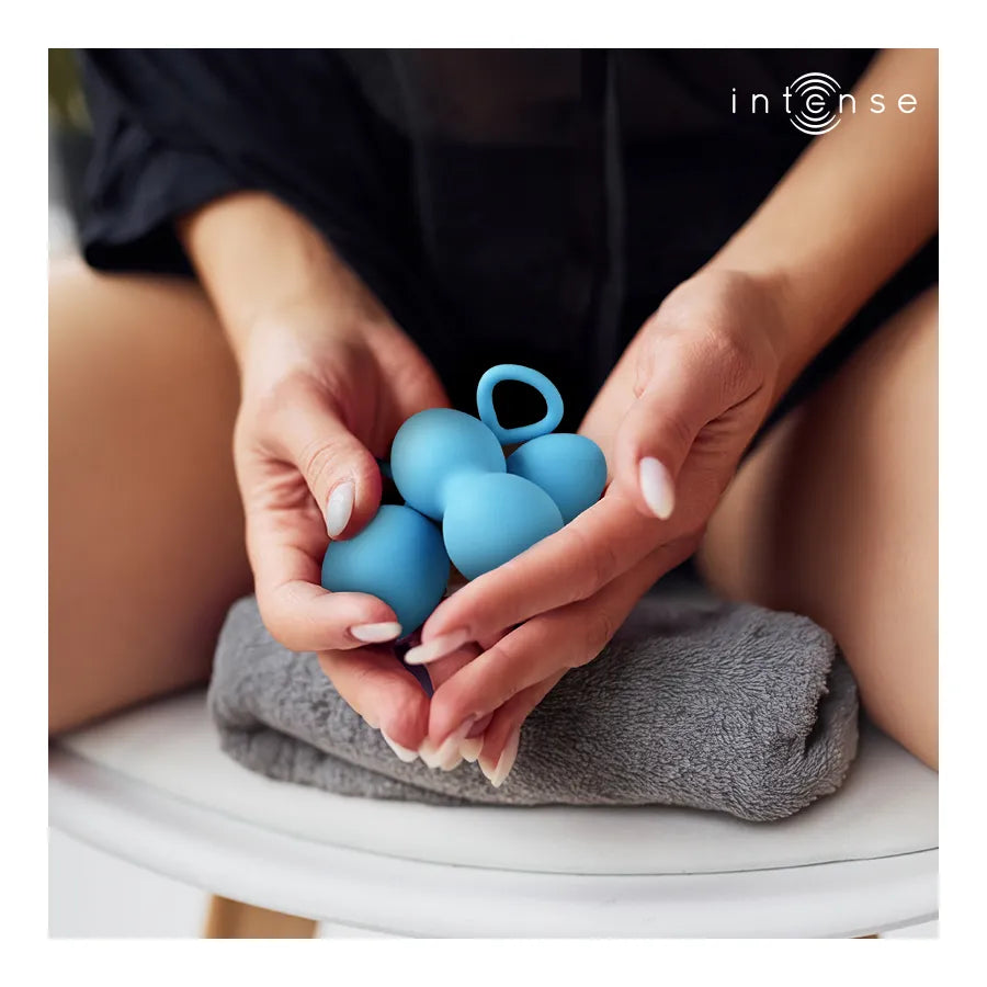 Boules de Kegel bleues en silicone médical, design moderne, tenues dans une main, pour renforcement pelvien féminin.